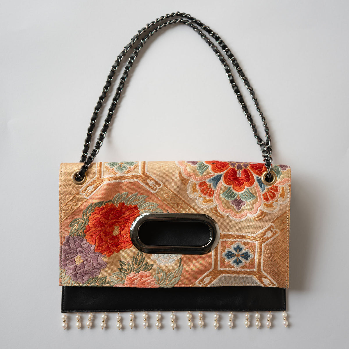 A clutch bag made from a vintage obi, featuring a scene of pine and plum blossoms.