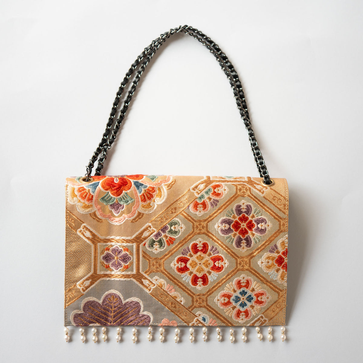 A clutch bag made from a vintage obi, featuring a scene of pine and plum blossoms.